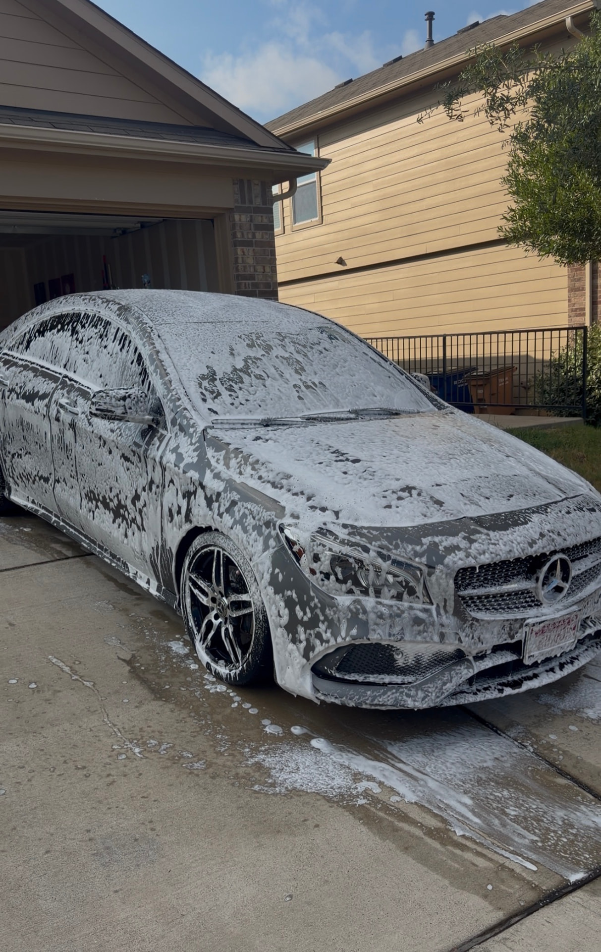 Gray Mercedes-Benz sedan covered in foam during a hand wash